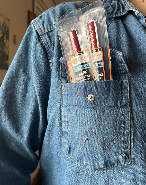Individually wrapped beef sticks sticking out of a denim pocket, indicating the product is available in physical, solid form.